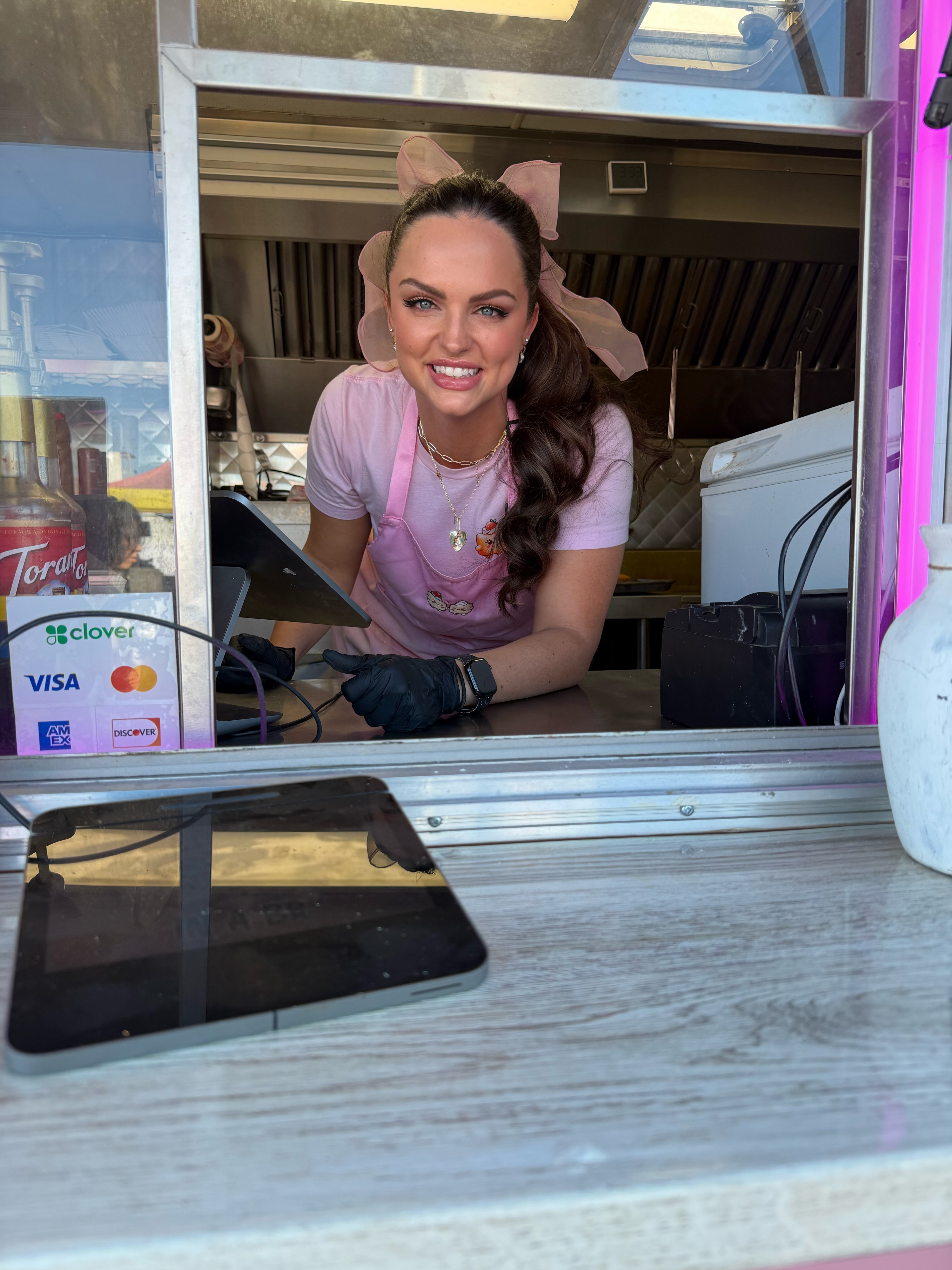 A smiling woman welcoming customers through the Beignets in a Box trailer window